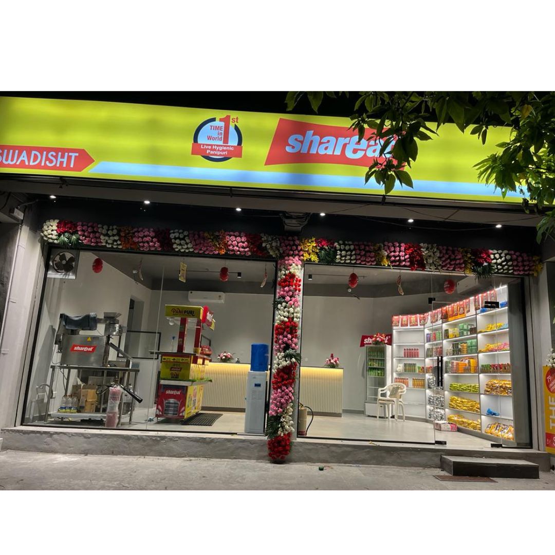 Illuminated ShareChat snack shop with floral decoration, shelves stocked with packaged snacks and drinks